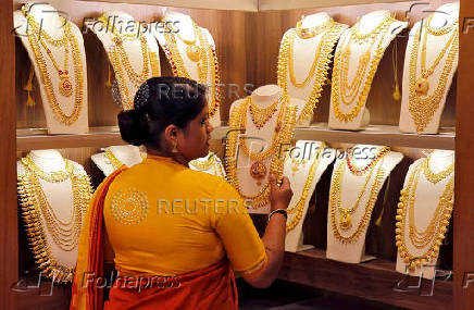 FILE PHOTO: A saleswoman picks gold necklaces to show it to a customer inside a jewellery showroom on the occasion of Akshaya Tritiya, a major gold buying festival, in Kochi