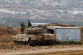 Israeli soldiers stand on a tank as they observe Gaza