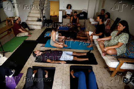 A photographer who survived the deadly October 7 attack by Hamas on the Nova festival sits with other survivors, in Caesarea