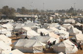 People gather near tents for the displaced who fled Aleppo countryside, in Tabqa