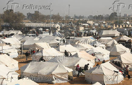 People gather near tents for the displaced who fled Aleppo countryside, in Tabqa