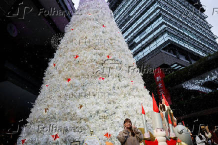 A woman poses for pictures in front of a Christmas tree in Taipei