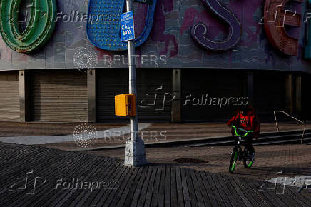 A boy rides a bicycle on the boardwalk of at Coney Island  in the Brooklyn borough of New York City