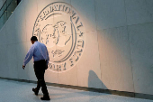 A man walks past the IMF logo at its headquarters in Washington