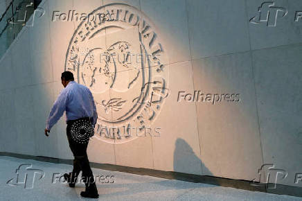 A man walks past the IMF logo at its headquarters in Washington