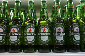 Bottles of Heineken beer are displayed on a shelf in a supermarket