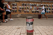People pass posters with pictures of hostages who were kidnapped during the deadly October 7 attack on Israel by Hamas, in Tel Aviv