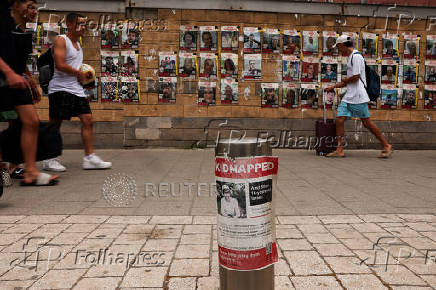 People pass posters with pictures of hostages who were kidnapped during the deadly October 7 attack on Israel by Hamas, in Tel Aviv