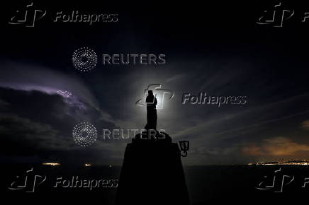 FILE PHOTO: A statue of the Madonna overlooks the sea as the  supermoon rises and a lightning storm strikes off the coast at Marfa Ridge, in the north of Malta,