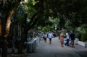 People walk in the neighborhood of Koukaki, in Athens