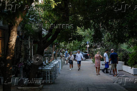 People walk in the neighborhood of Koukaki, in Athens