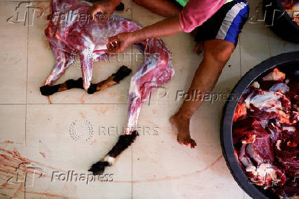 A man prepares freshly slaughtered goat meat to be distributed free for people, during a sacrificial ritual of Eid al-Adha celebrations in Jakarta