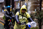 Delivery workers ride their bikes during a rainy day in New York