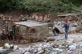 People search for victims near destroyed bridge in a flooded residential area in Buturovic Polje