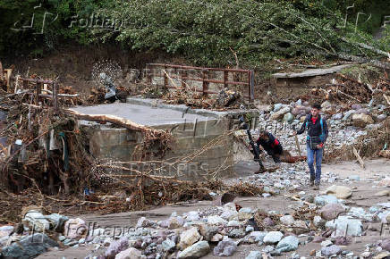 People search for victims near destroyed bridge in a flooded residential area in Buturovic Polje