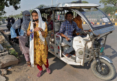 Employees disembark from a battery rickshaw as they arrive for work outside the HCLTech office on outskirts of Lucknow