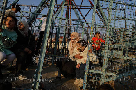 Girls with their faces painted with the flag adopted by the new Syrian rulers sit on a swing boat at an amusement park, in Douma