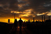 The sun sets behind the Lower Manhattan skyline in the Brooklyn borough of New York City