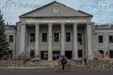 A resident rides a bicycle in front of a building damaged by Russian military strikes in Pokrovsk