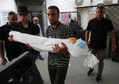 A man carries the body of a Palestinian child killed in Israeli strikes, in Rafah