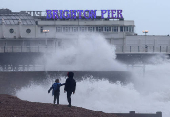 People walk on the beach near Palace Pier as Storm Nelson arrives at Brighton