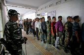 Security personnel stand in a queue to cast their postal ballots at a polling station in Agartala