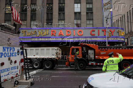 Officers from the New York City Police Department (NYPD) stand guard beside trucks from the New York City Department of Sanitation outside Radio City Music Hall