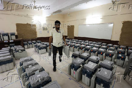 A polling official holds an Electronic Voting Machine (EVM) inside a strong room at a distribution centre ahead of the first phase of the election, in Bikaner