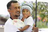 A man holds his son while he waits to welcome Pope Francis before he arrives in Dili