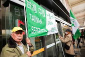 Protesters holding flags supporting Taiwan's independence stand outside the Songshan Airport while Shanghai Vice Mayor Hua Yuan arrives for the annual city forum in Taipei