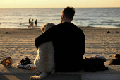 A man wraps his arm around a dog on ANZAC Day at Coogee Beach in Sydney