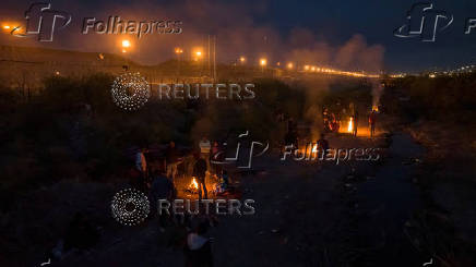 Migrants encircle fire to stay warm as they search for entry point into U.S. from bank of Rio Grande river