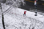 A child runs along a sidewalk holding a snowball during the city's first snowfall of the season, on the first day of winter in the Queens borough of New York City