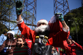 Guatemalan firefighter dressed as Santa Claus rappels down the Vacas Bridge to give toys to children, in Guatemala City