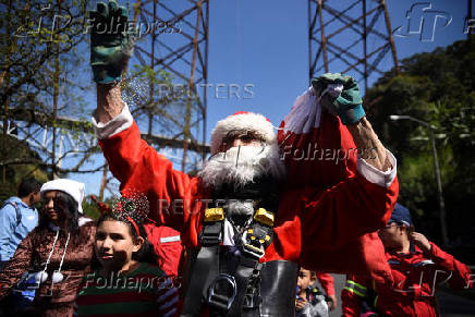 Guatemalan firefighter dressed as Santa Claus rappels down the Vacas Bridge to give toys to children, in Guatemala City