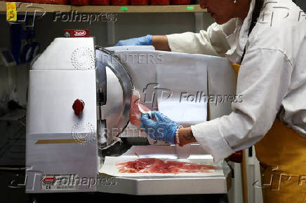 A vendor slices dry-cured ham at a market stall in Rome