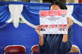 A woman shows the ballot for Jakarta governor election before voting at a polling station during regional elections in Jakarta