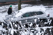 A person cleans snow from their car during the city's first snowfall of the season, on the first day of winter in the Queens borough of New York City