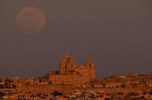 The full moon, also known as the Pink moon, rises behind St Paul's Metropolitan Cathedral in the medieval city of Mdina