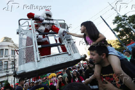 A firefighter dressed as Santa Claus greets a girl during Christmas season celebrations in Valparaiso