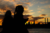 The sun sets behind the Lower Manhattan skyline in the Brooklyn borough of New York City