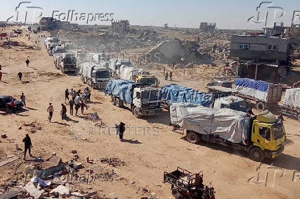 Palestinians run towards aid trucks after crossing into the Gaza Strip, in Rafah