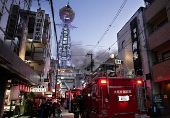 Smoke rises from a fire site at a commercial building near a famous tourist landmark Tsutenkaku Tower, in Osaka