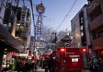 Smoke rises from a fire site at a commercial building near a famous tourist landmark Tsutenkaku Tower, in Osaka