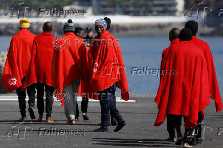 Migrants walk towards a Red Cross tent to be treated in the port of Arguineguin