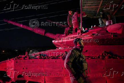 Israeli soldiers gather near a military vehicle after returning from Lebanon, following a ceasefire between Israel and Iran-backed group Hezbollah, near Kiryat Shmona