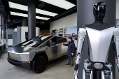 A Tesla Bot stands on display as people look at a Tesla Cybertruck at a Tesla showroom in New York City