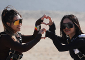 Professional skydivers cheer and make love sign gestures with their hands before flying over the historical site of Giza Pyramids, in Giza