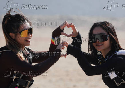 Professional skydivers cheer and make love sign gestures with their hands before flying over the historical site of Giza Pyramids, in Giza