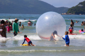 Crianas usam bolhas e colches inflveis dentro do mar, na praia Grande